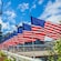 A series of American flags flying next to a Navy ship